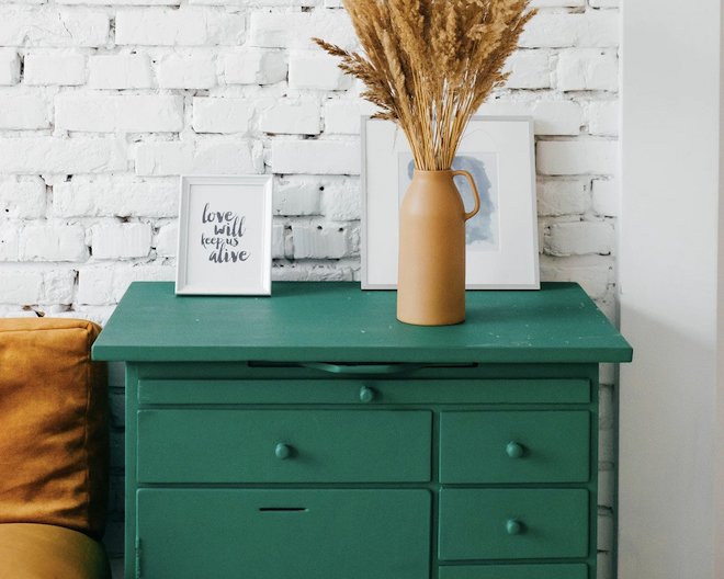 an image of a teal coloured table with a brown vase on top of it.